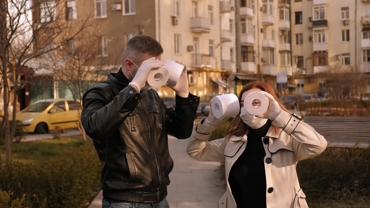戴着口罩和手套的情侣们在街上用卫生纸玩得很开心。视频下载