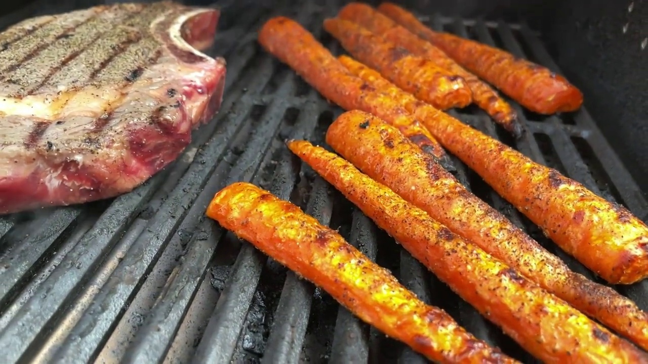 厚切生调味牛肉肋眼牛排和有机胡萝卜与火焰木炭烧烤4K视频视频下载