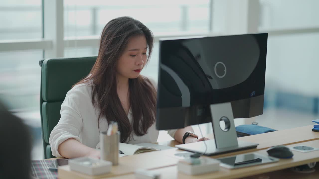 一位亚洲华人妇女在她工作的地方的台式机前打字视频下载
