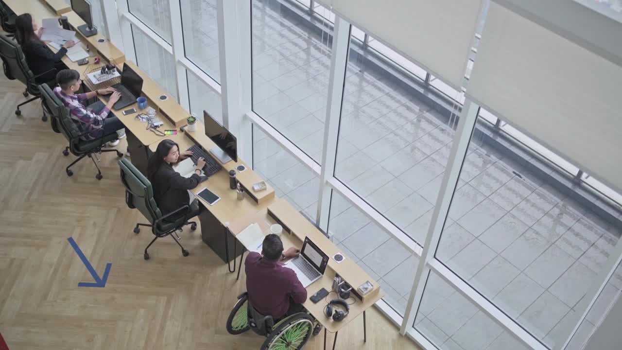 坐在轮椅上的印度商人正在创意办公室与他的中国女同事讨论视频下载