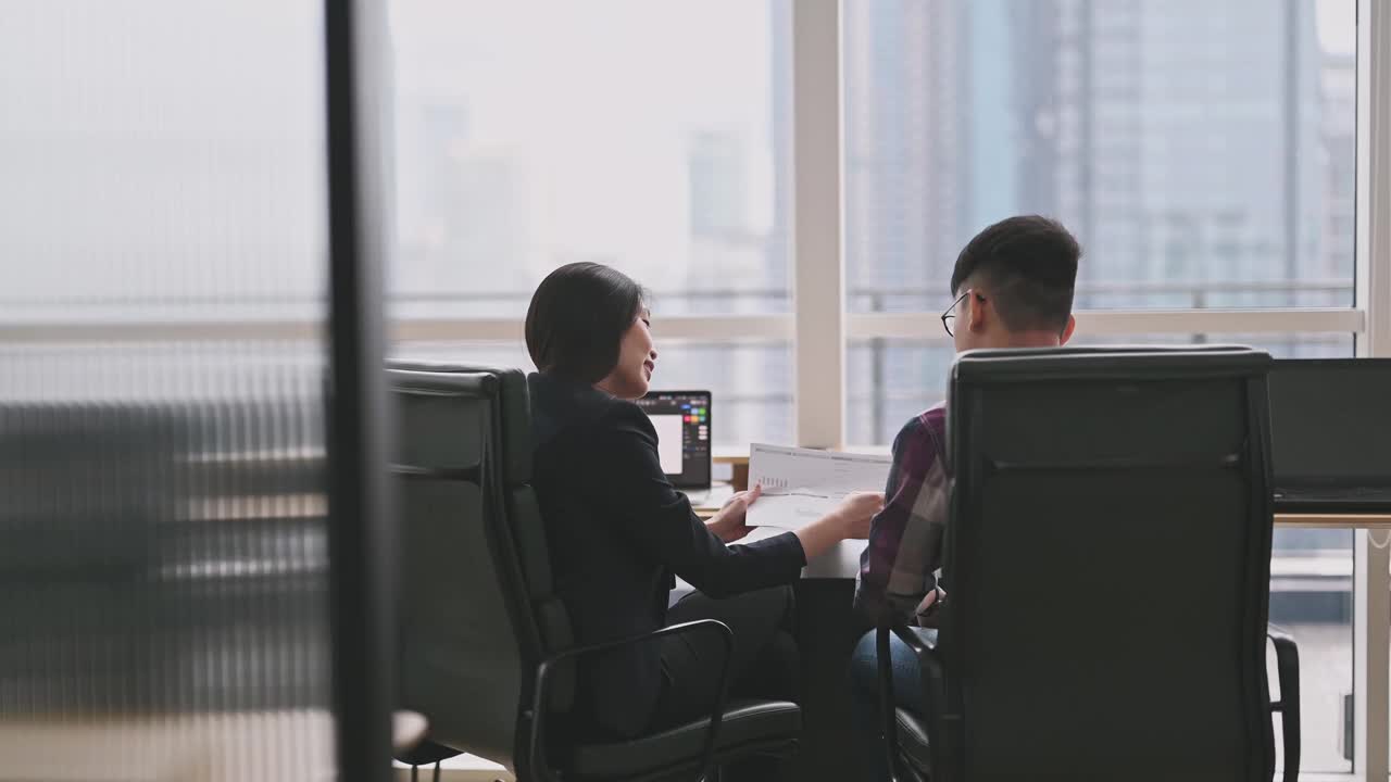 一位亚洲华裔女同事在办公室向她的学员解释视频素材