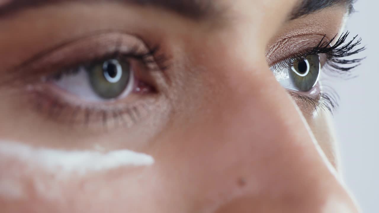 一个女人在工作室背景下涂抹润肤霜的4k视频片段视频下载