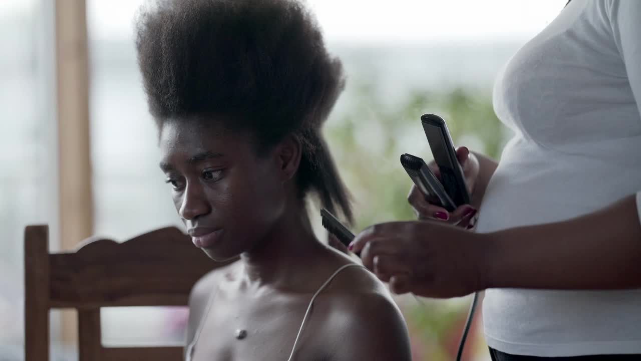一位正把头发拉直的年轻女子。准备编辫子视频素材