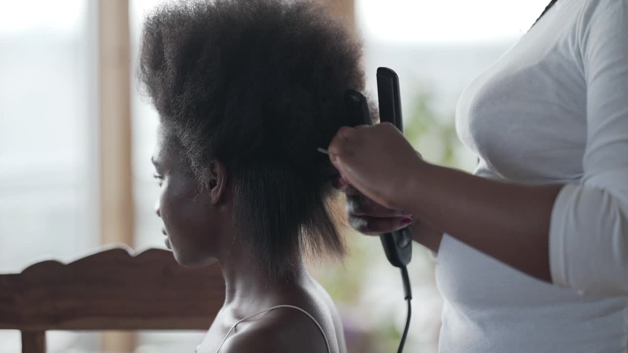一位正把头发拉直的年轻女子。准备编辫子视频素材