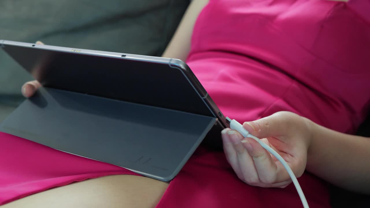 女人的手把黑色闪电充电线插到电脑数码平板电脑上视频下载