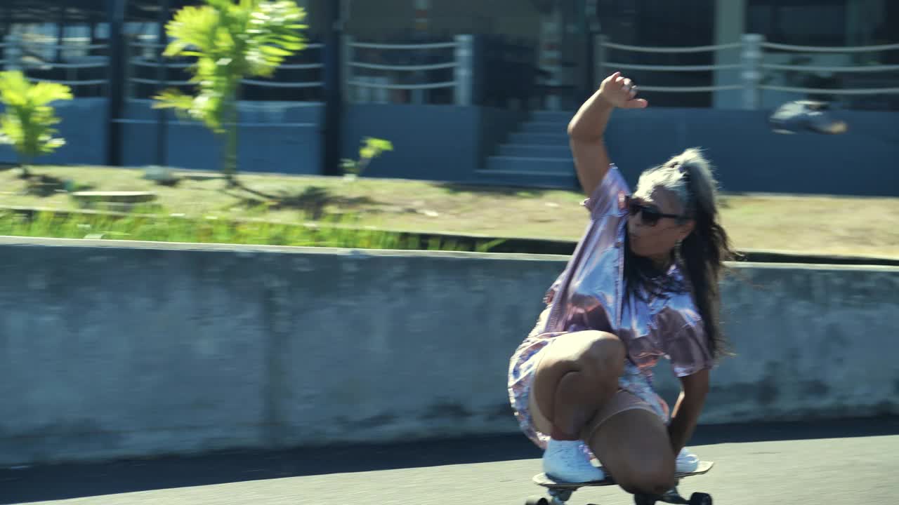 幸福的资深运动妇女拉丁美洲和西班牙裔戴太阳镜和灰白头发的年龄53岁玩滑板在一个阳光明媚的日子。老年人在运动的概念。视频素材