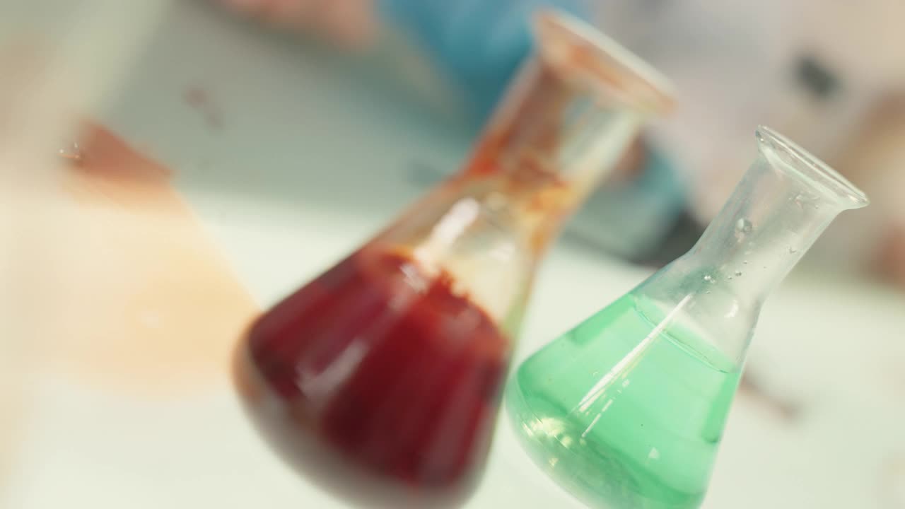 孩子们在实验室里做科学实验。用移液管浇注多种颜色的液体。近距离视频素材