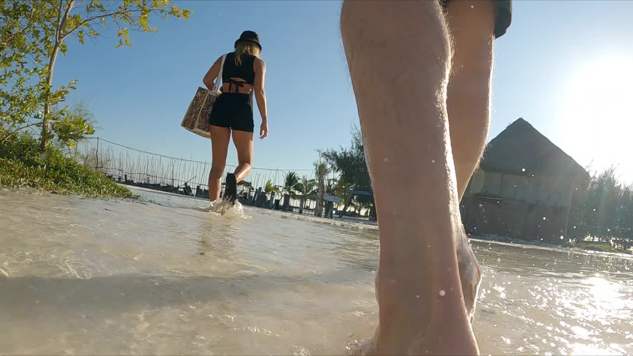 一对夫妇在热带海滩上散步。近距离步行视频下载
