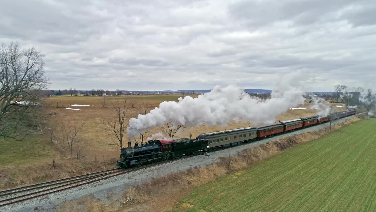 无人机视野的蒸汽机车与旅客车厢接近与一个满头的蒸汽在农村在冬天的一天视频下载