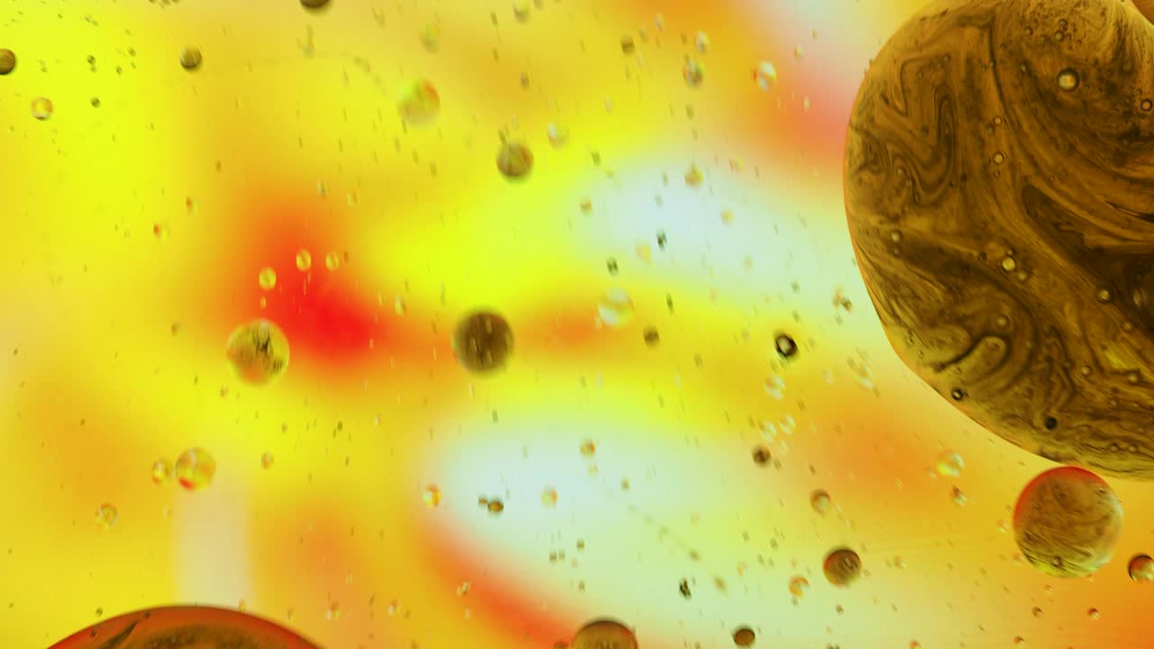 行星形状的液体气泡，漂浮在五颜六色的液体表面。视频素材