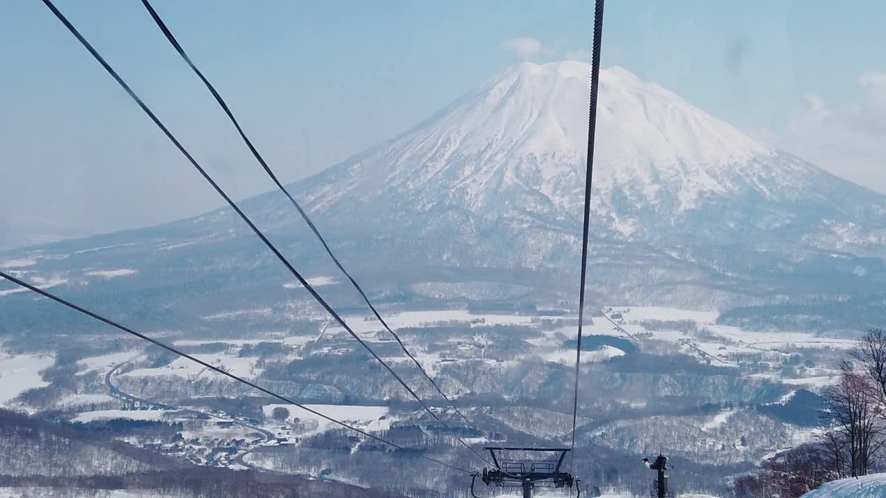 在日本北海道二世子滑雪村的大平夫滑雪附近，慢动作滑雪缆车高到山顶的大约亭山背景视频下载