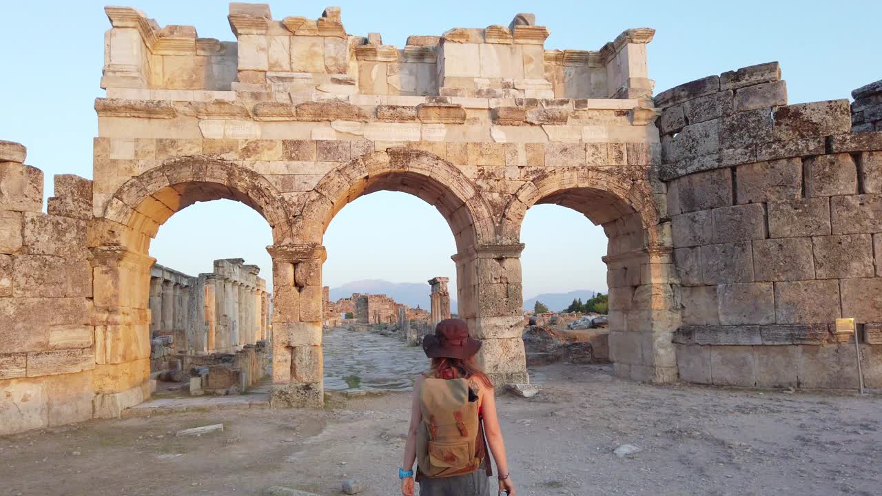 一名摄影师游客正走向位于帕穆克卡莱希拉波利斯古遗址中的Frontinus门视频下载