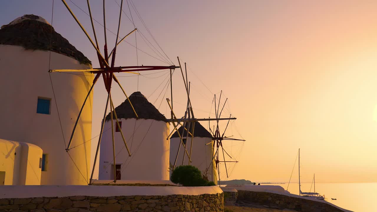 在希腊米科诺斯岛日落时，视差追踪着希腊标志性的古老风车视频素材