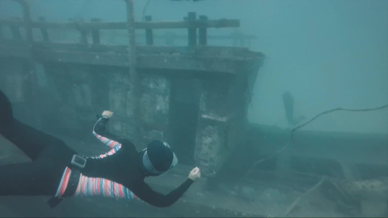 女自由潜水员在沉船上方水下游泳视频下载