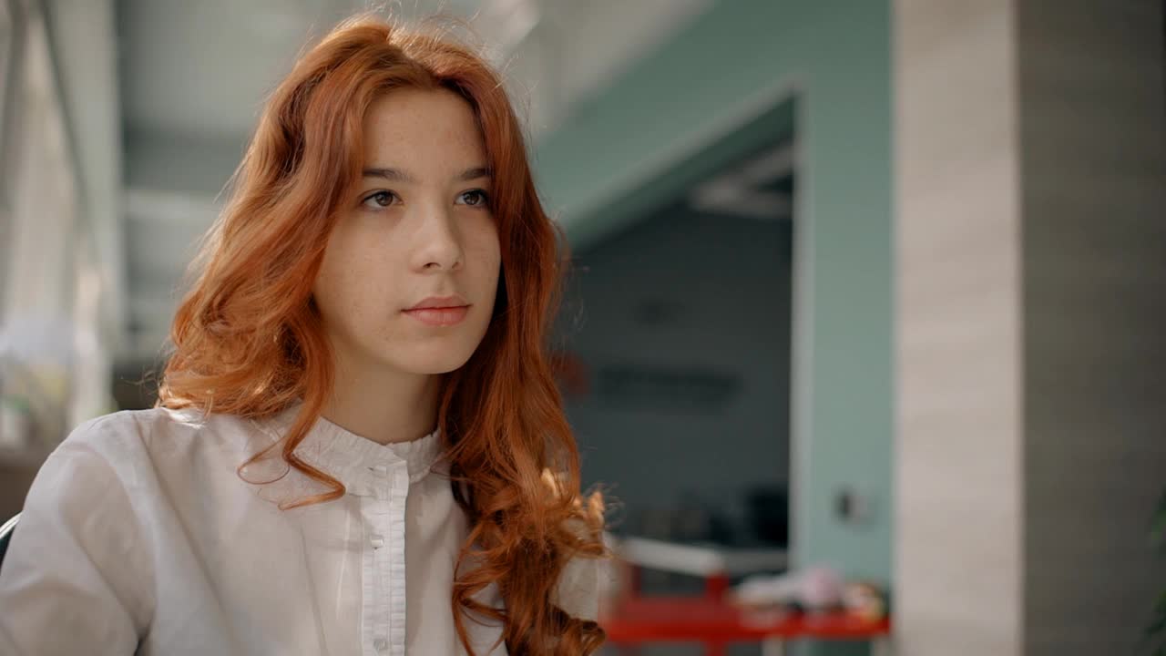 漂亮的年轻女子，红头发，白衬衫，坐在办公室大厅里聊天视频下载