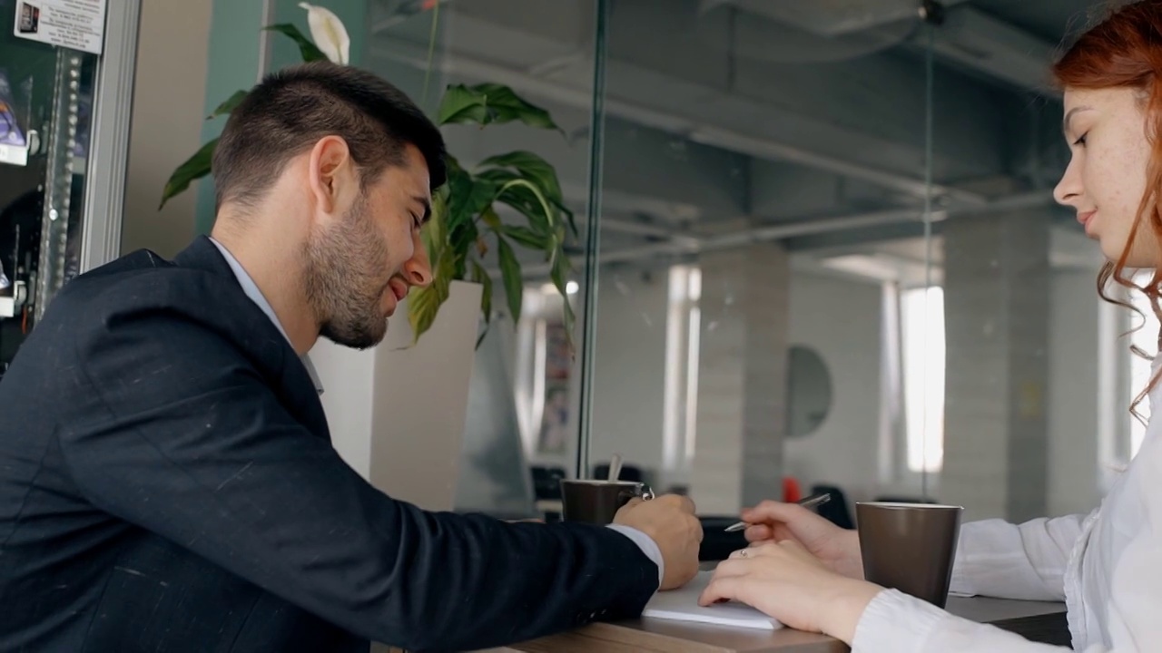办公室里有两个同事在一起做这个项目:一个穿西装的男人在做笔记视频下载