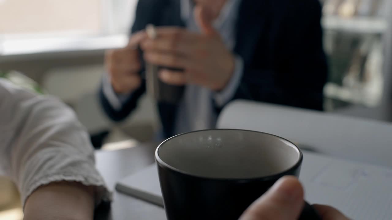 年轻的商业人士在工作时间在办公室的桌子上喝咖啡视频下载