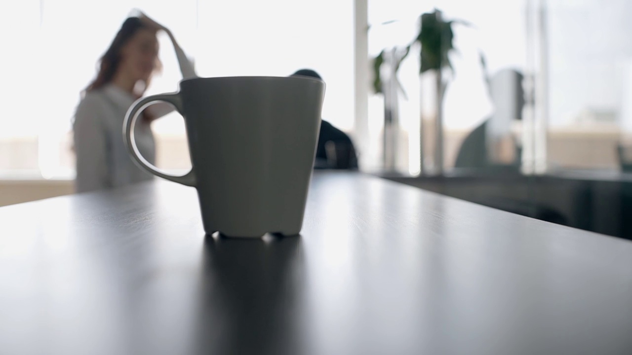 咖啡杯放在柜台上，背景是聊天的同事视频下载