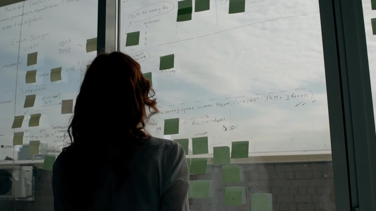 一个年轻的女人在窗户上贴着天空的图片，并在上面写字视频下载