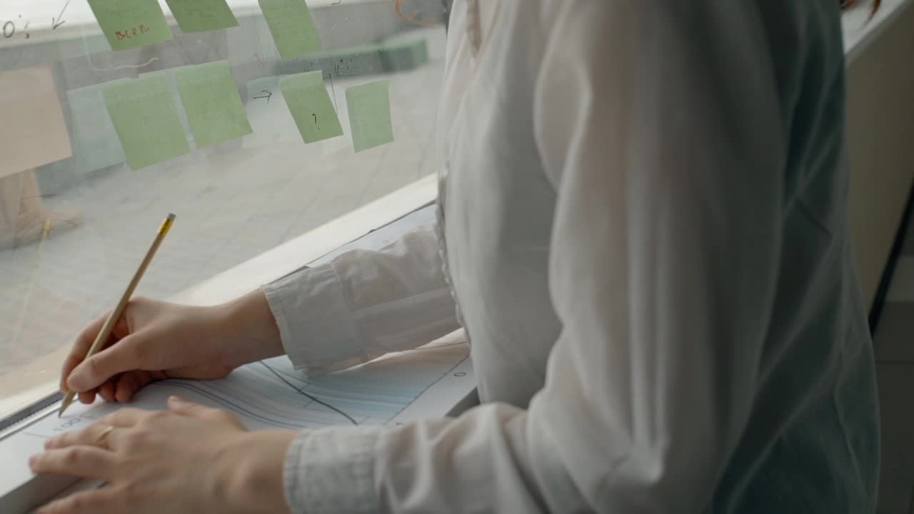 年轻的女性专业人员站在现代办公室的窗口写文件视频下载