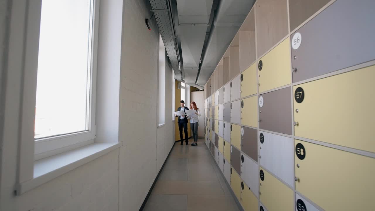 一男一女站在公司走廊上讨论投资项目视频下载