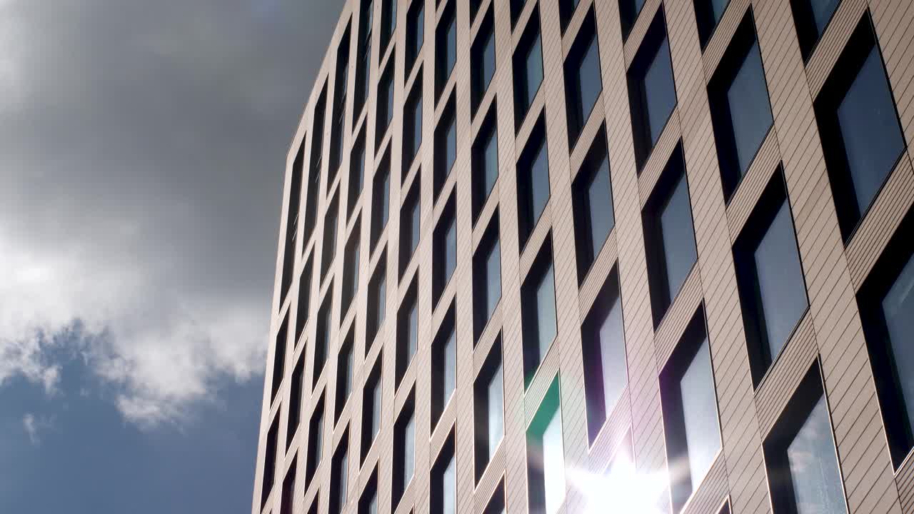 在欧洲英国伦敦，仰望摩天大楼公司办公大楼总部，引人注目的灰色云层通过玻璃反射的阳光，呈现出忧郁的黑暗外观视频素材