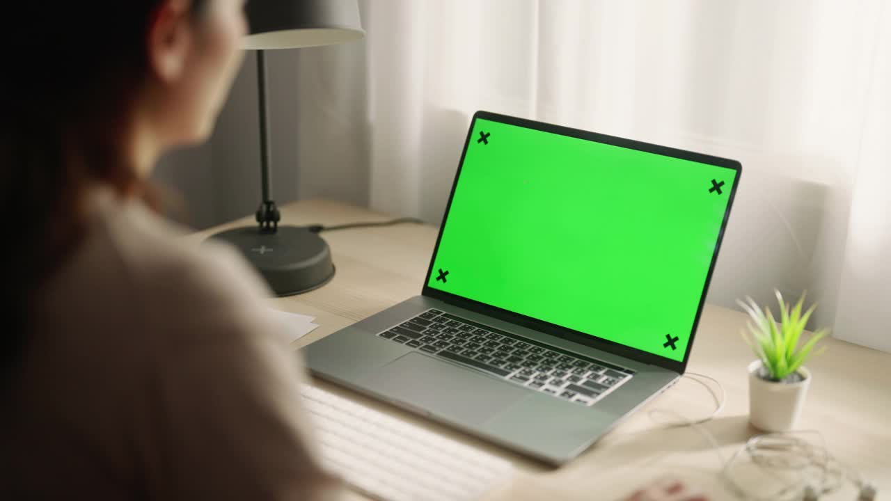 亚洲妇女使用笔记本电脑与绿色屏幕显示在家里视频下载
