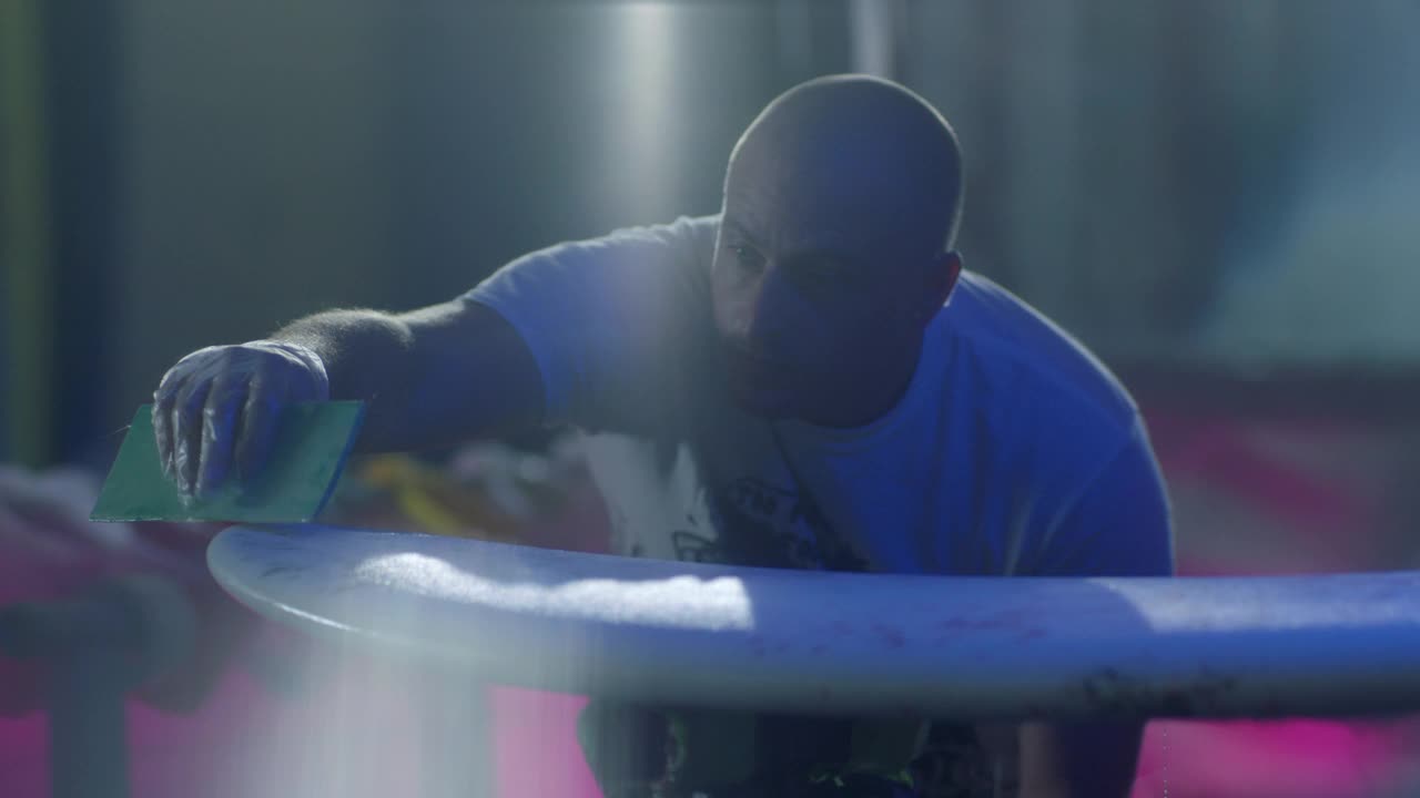 一个男人在冲浪板上涂抹产品的SLO MO MS视频下载