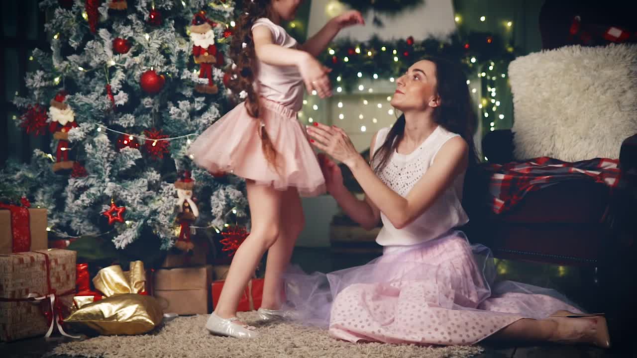 小女孩在圣诞树下拥抱她的妈妈。视频素材