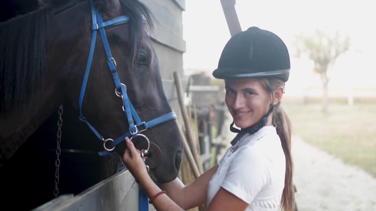 漂亮的年轻女人穿着骑马服抚摸着她的马视频下载