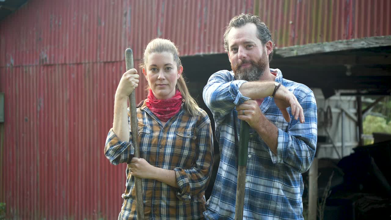 一对在家庭农场工作的夫妇，站在谷仓前视频下载