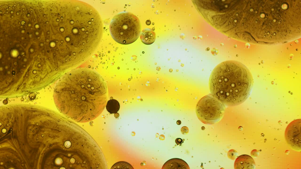 一个行星形状的液体气泡，漂浮在黄色液体的表面。视频素材