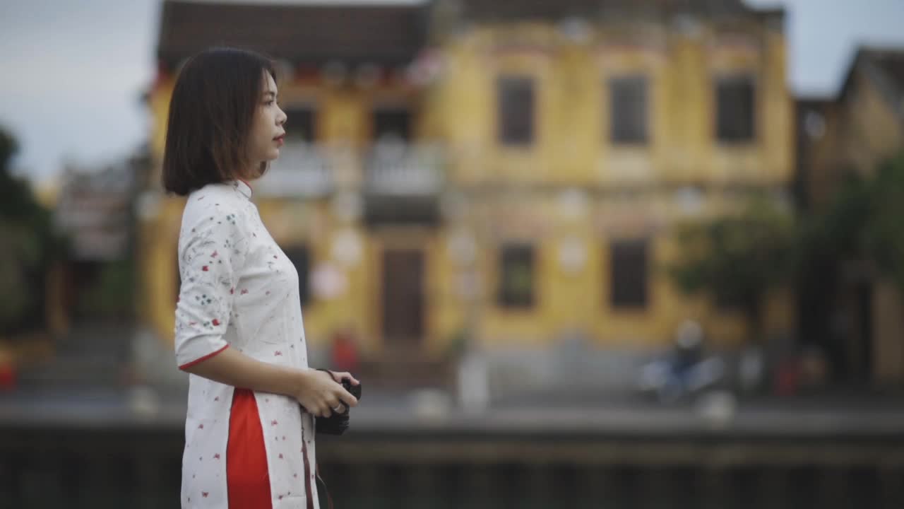 慢动作妇女游客穿着奥雅爱越南传统服装在会安拍照视频下载