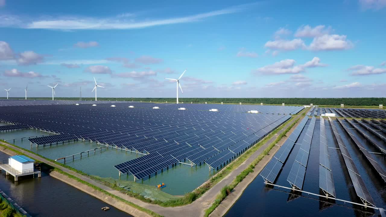 平原地区的太阳能发电站和远处的风力涡轮机。中国江苏省盐城市视频素材
