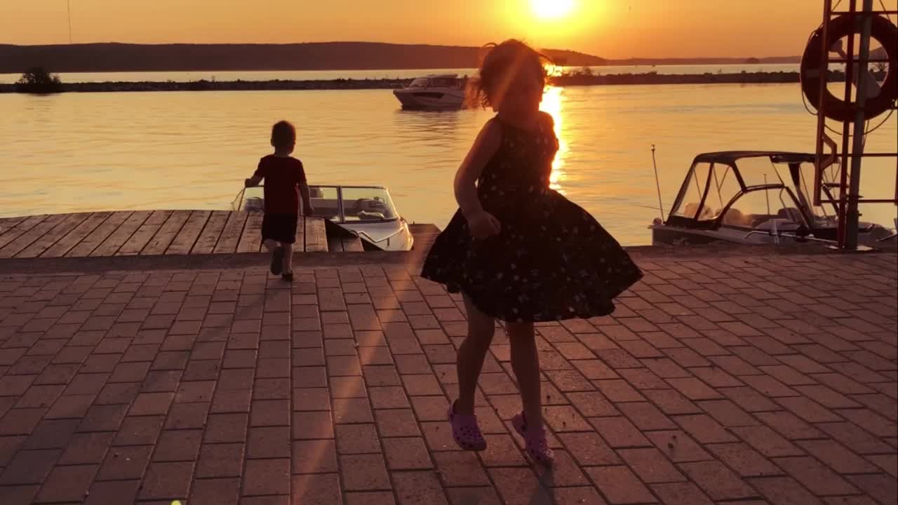 孩子，白人女孩，6岁，在夕阳的映衬下在城市堤坝上跳舞。温暖的夏夜，好心情。视频素材