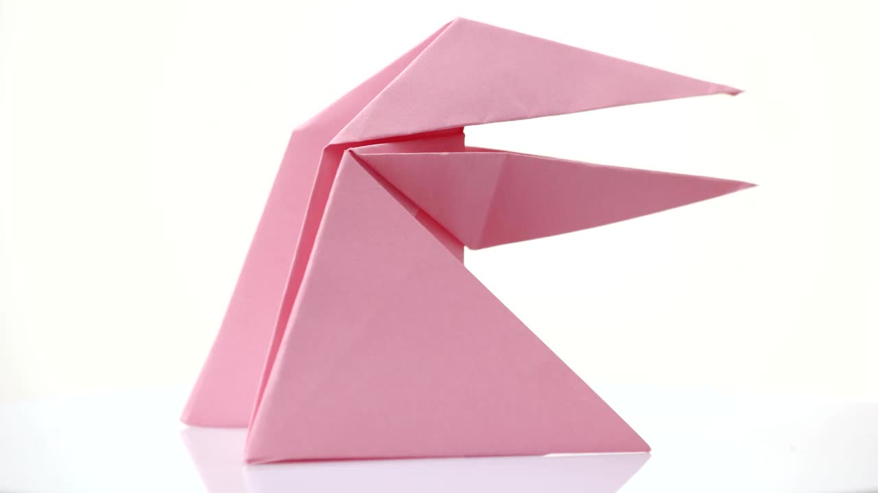 粉红色的折纸青蛙被隔离在白色上。视频下载