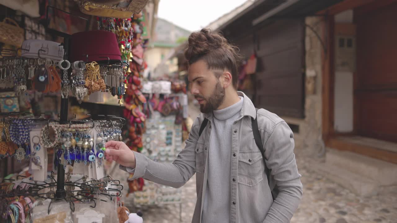 年轻的男性游客在当地的街头市场寻找纪念品视频下载
