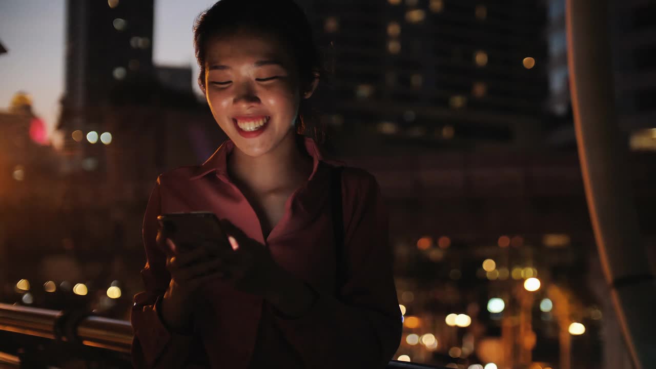 晚上在城市里和美丽的散景一起用手机的女人视频素材