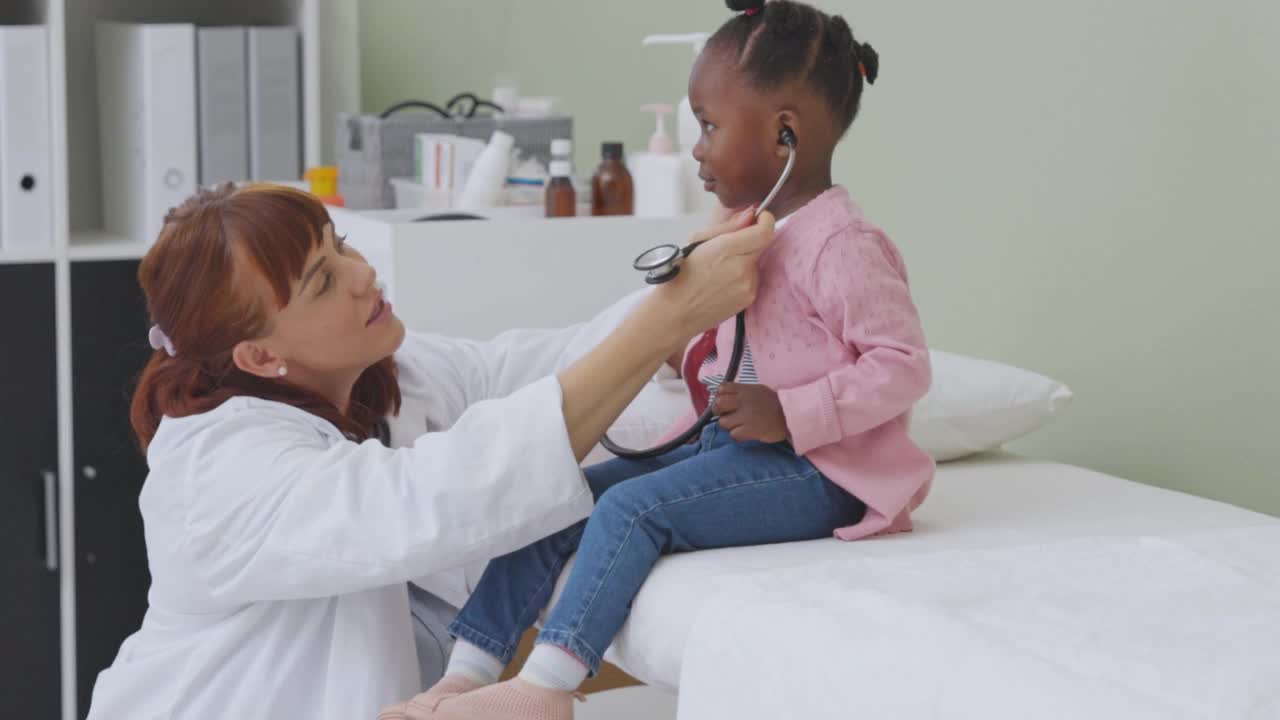 一个友好的医生让一个小女孩用听诊器给她检查的4k视频片段视频素材