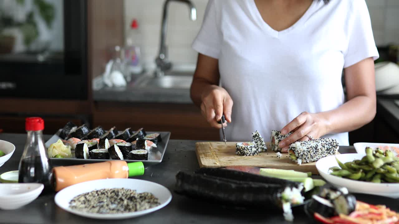 女寿司师傅把寿司卷从里到外切成一片，放在砧板上视频下载