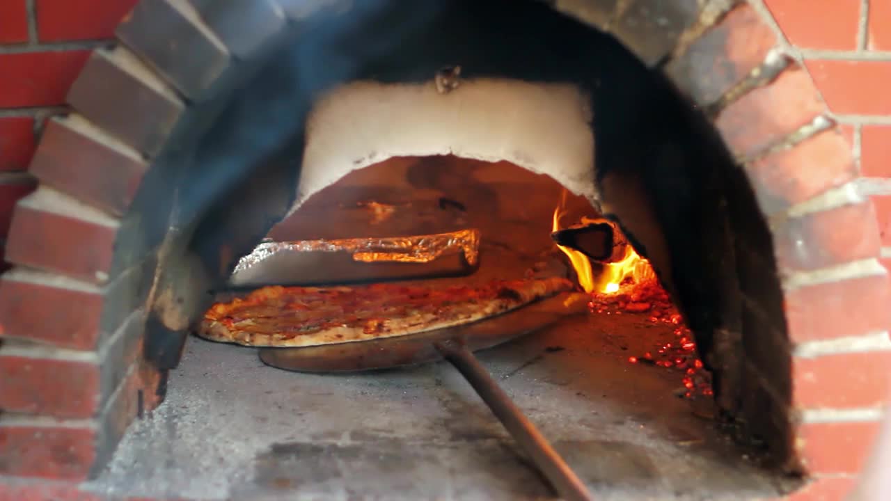 披萨厨师烹饪披萨在木烧砖炉视频素材