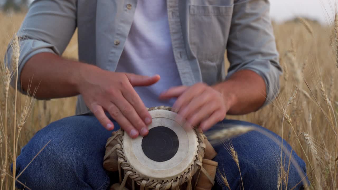 一个男人坐在麦田里吹着鼓视频素材