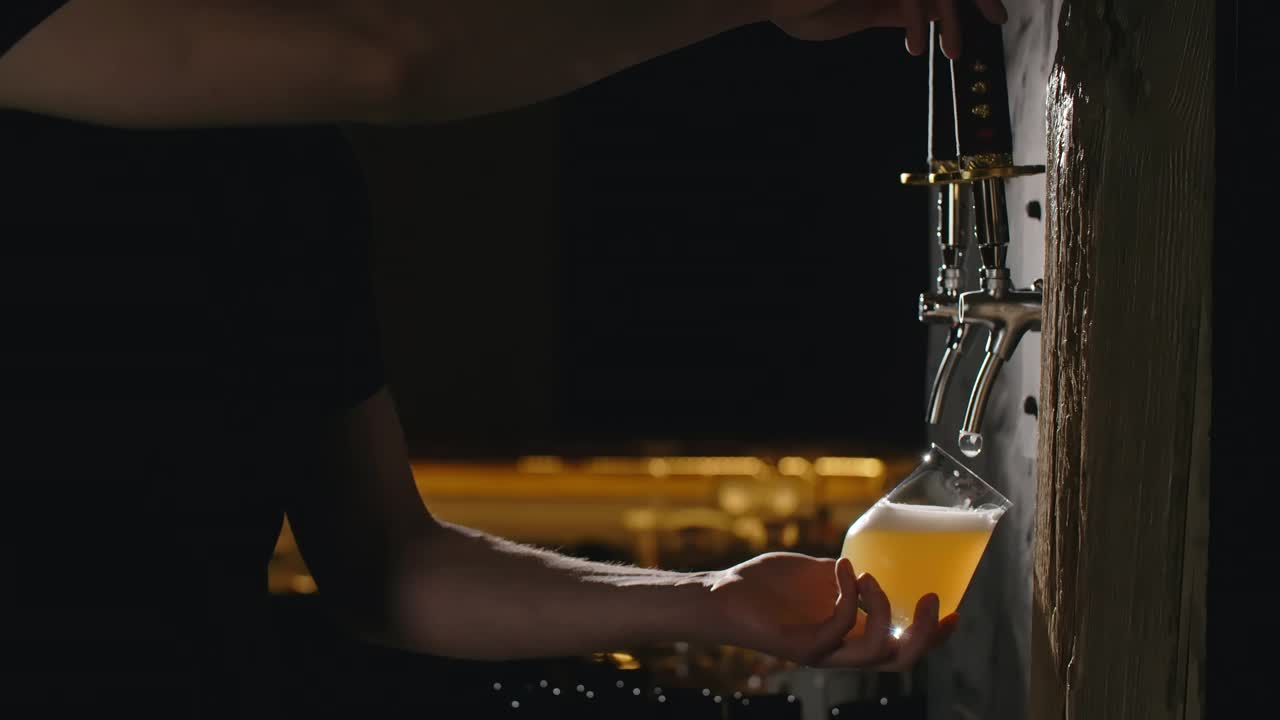 酒吧招待员用慢动作将未过滤的淡啤酒从啤酒龙头倒进玻璃杯，在酒吧里倒小麦啤酒，4k 120帧普罗雷斯HQ视频下载