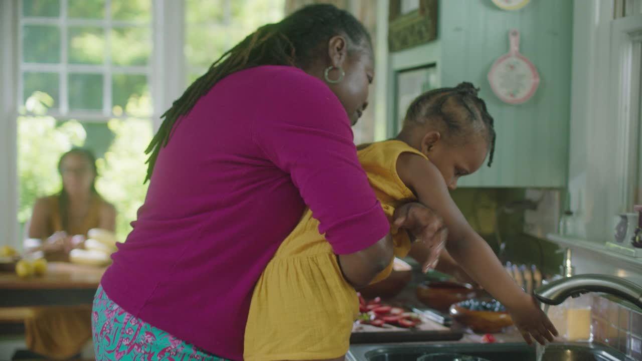 一个成熟的女人抱着一个小女孩洗手视频素材