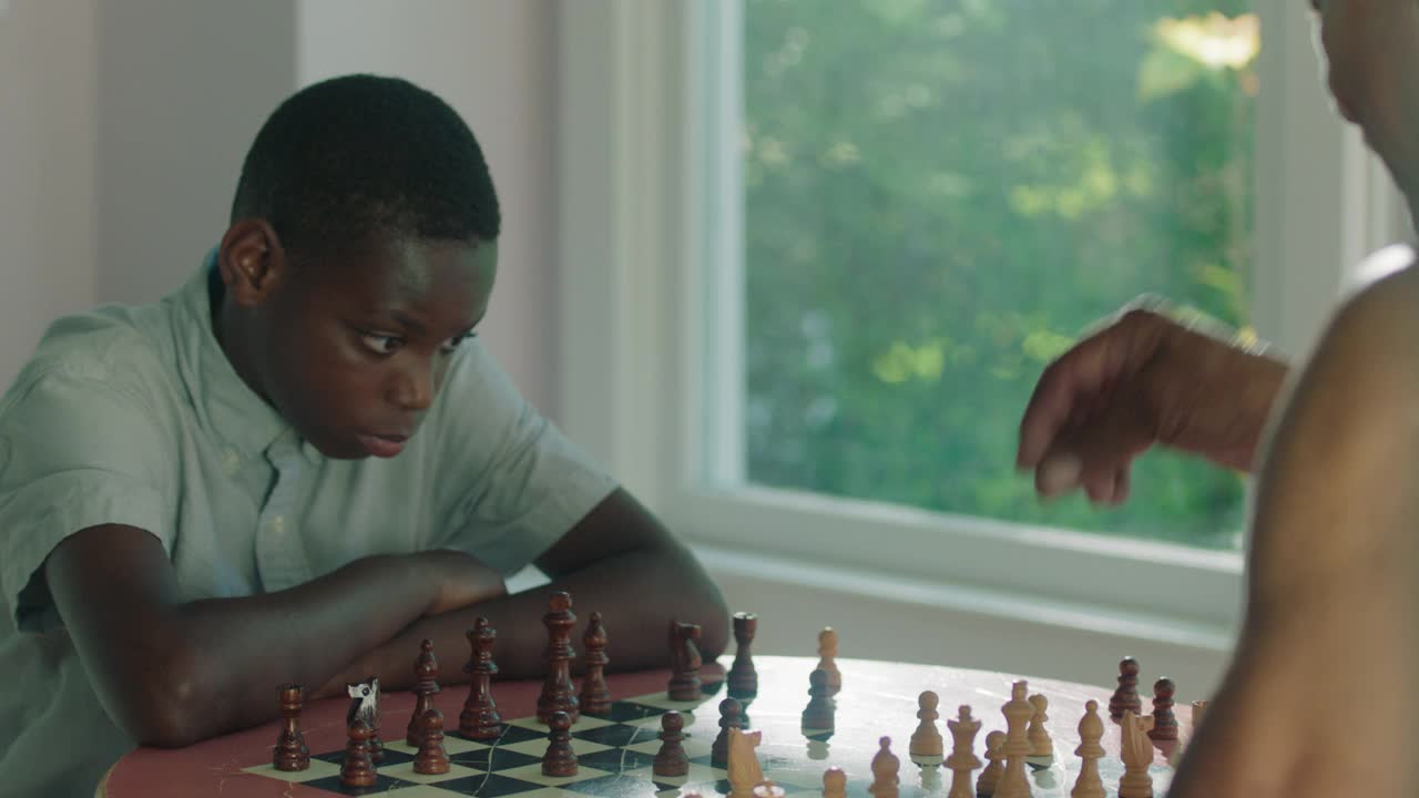 一个专注的男孩和一个成熟的男人下棋视频素材