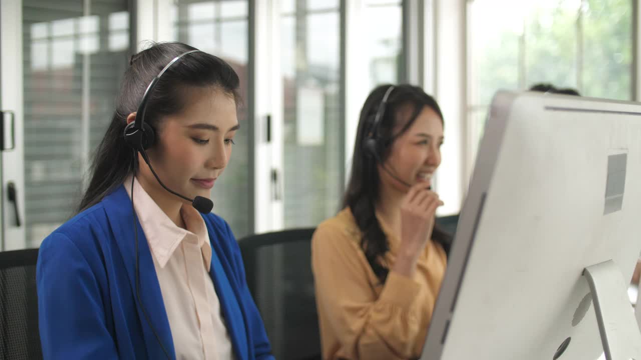 年轻的女性呼叫中心工作人员在她的工作站与客户交谈视频素材