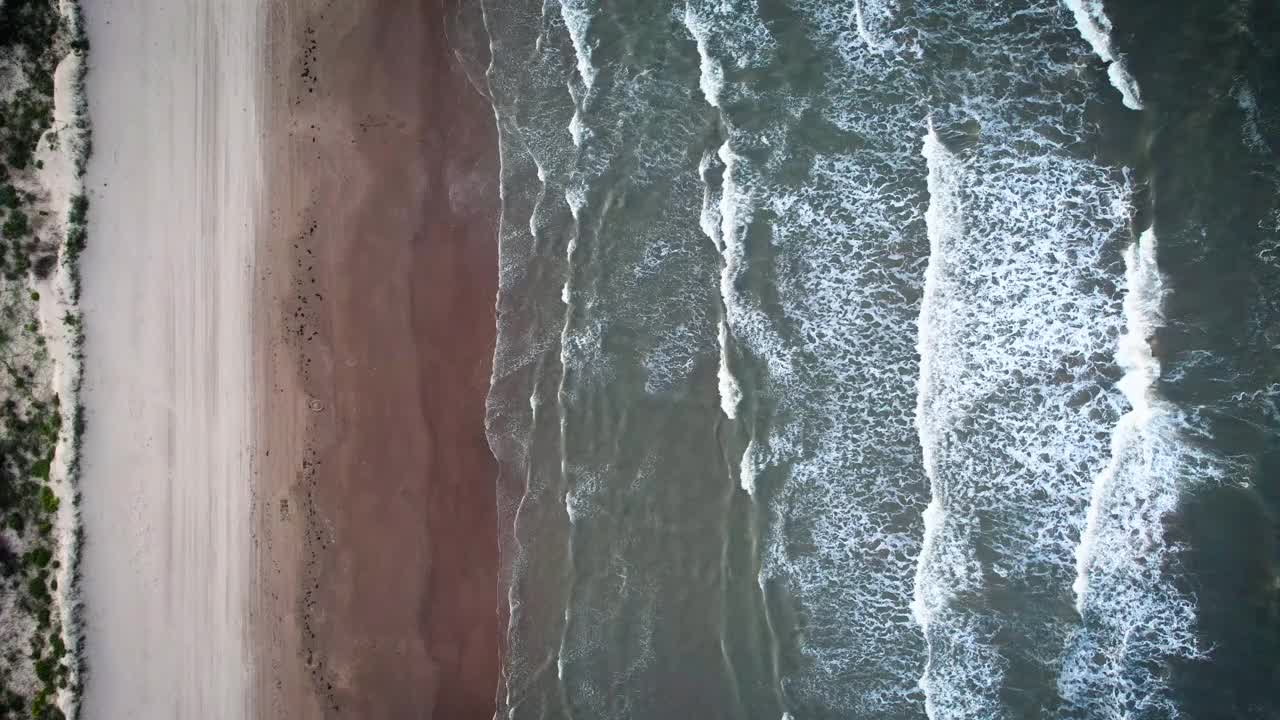 从上往下看，海浪冲击着沙滩视频下载