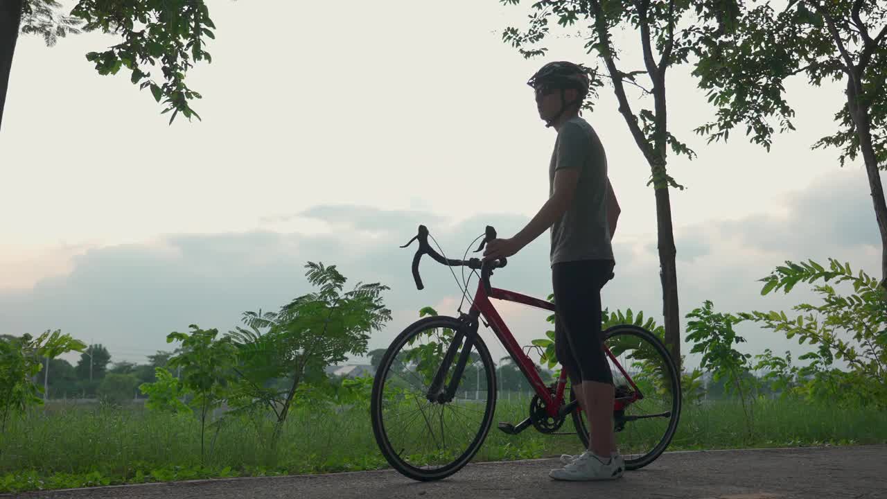 亚洲活跃男性晚上在公园骑自行车健身。年轻的运动员健康和坚定的人在运动服锻炼自行车运动为他的健康和健康的健康在公园。视频素材