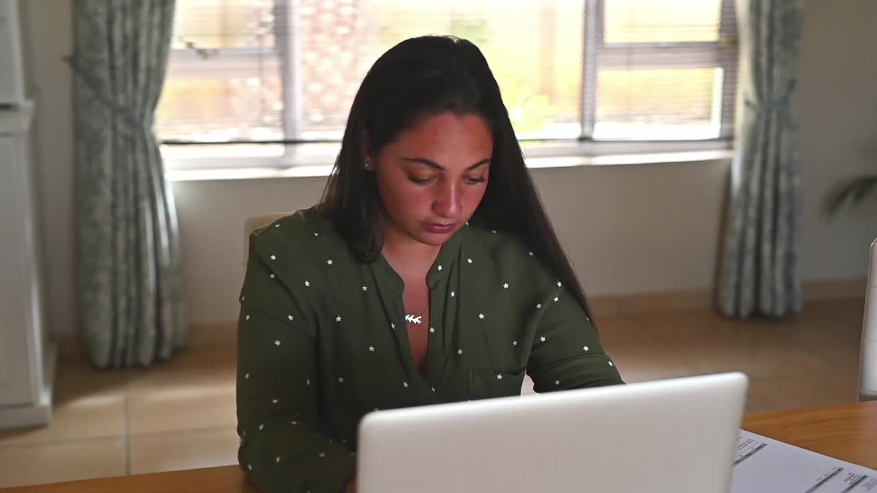一个年轻女子在家里用笔记本电脑工作时看起来压力很大的4k视频片段视频素材
