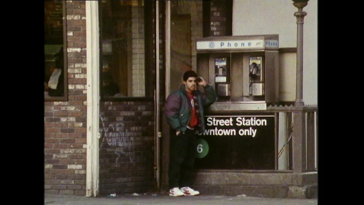一名男子在哈莱姆区的街道上使用公用电话;1989视频素材